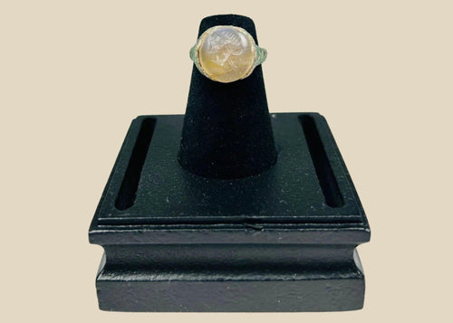 Ancient Indo-Greek ring from modern Afghanistan, Pakistan, or Northern India, circa 2nd–1st Century BCE, featuring a carved garnet bezel depicting a bearded male bust in profile. The metal band shows natural patina, reflecting over 2,000 years of history and the Hellenistic-Indian artistic fusion of the Indo-Greek Kingdom.