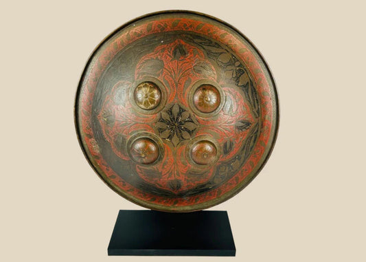 Small circular Indo-Persian Dhal shield, 11 inches diameter, lacquered black and red with damascened foliate motifs, four raised bosses, interior grips with knuckle-guard cushion, well-preserved antique.