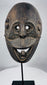 Indonesian ritual mask from West Timor with pierced eyes, open mouth, and weathered carved wood surface.