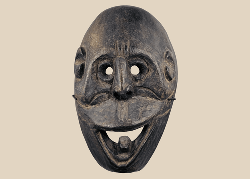 Carved wooden ritual mask from Fatuleu Village, West Timor, featuring large circular eyes and a protruding tongue, circa 1930.