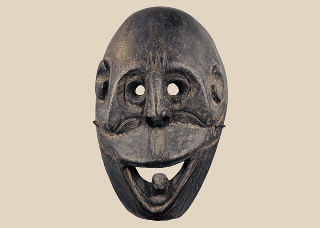 Carved wooden ritual mask from Fatuleu Village, West Timor, featuring large circular eyes and a protruding tongue, circa 1930.