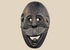 Carved wooden ritual mask from Fatuleu Village, West Timor, featuring large circular eyes and a protruding tongue, circa 1930.