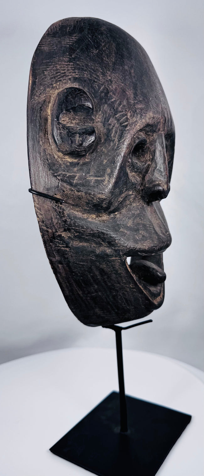 Circa 1930 tribal mask from West Timor carved from a single piece of hardwood and mounted for display.