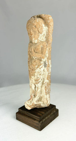 Iron Age terracotta fertility goddess figurine from the Levant, circa 600–300 BCE, stylized female form with one arm raised to the breast; faint red and white pigment traces visible on the surface, symbolizing abundance and protection.