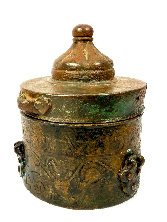 Medieval Islamic bronze writing vessel with a conical domed lid, small perforations along the upper band, and aged brown and green patination.