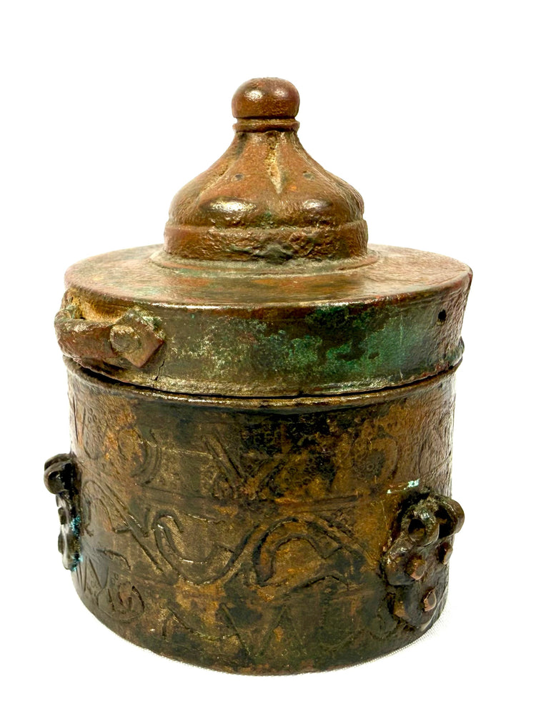 Medieval Islamic bronze writing vessel with a conical domed lid, small perforations along the upper band, and aged brown and green patination.