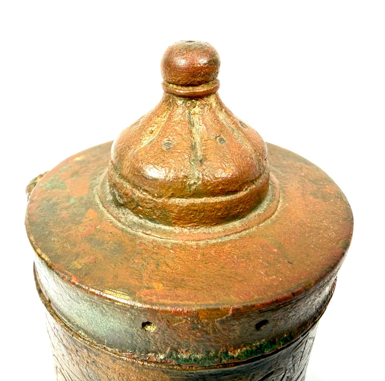 Islamic bronze inkwell with preserved metal attachment elements, small lid perforations, and partially worn geometric engravings.