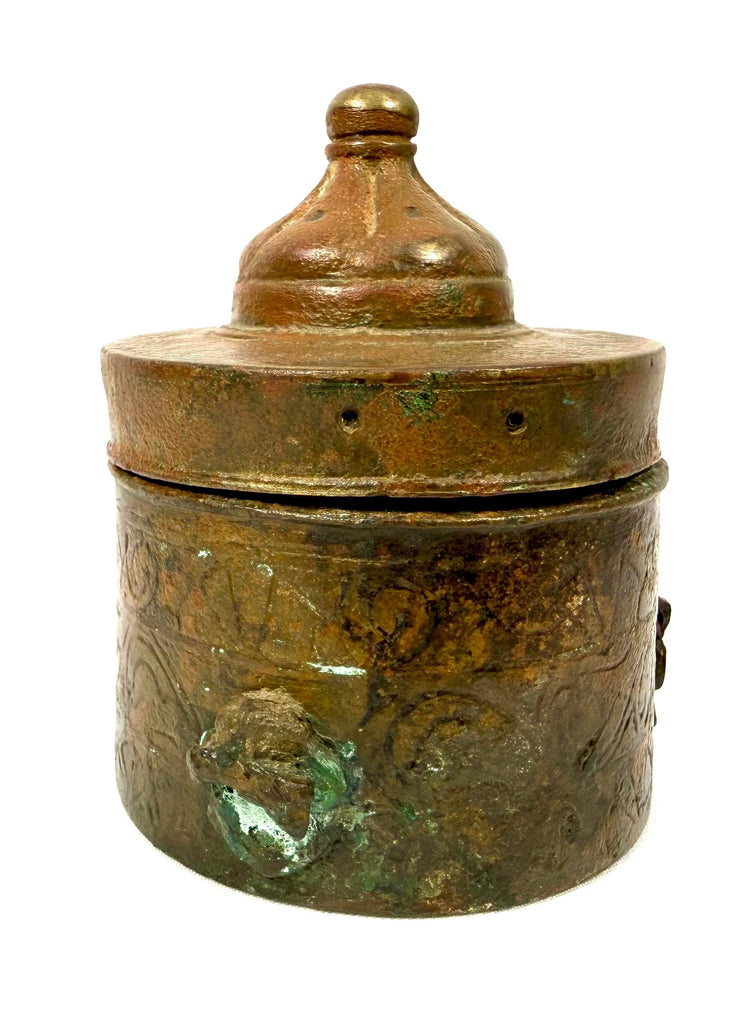 Medieval Islamic bronze inkwell displaying engraved curvilinear ornamentation, localized oxidation, and centuries-old surface wear.