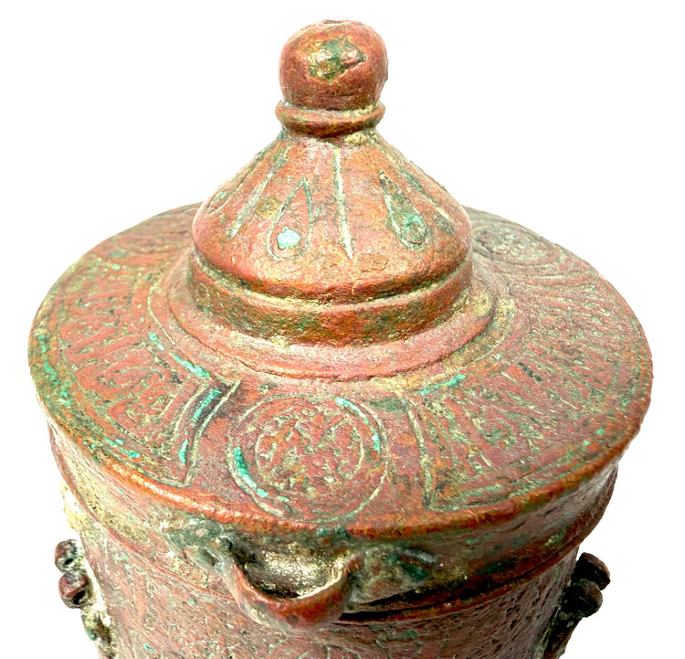 Islamic Golden Age bronze inkwell showcasing continuous engraved motifs across its cylindrical body and traditional metalworking craftsmanship.