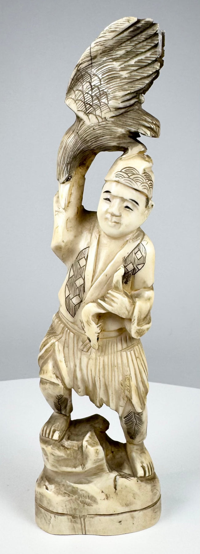 Three-quarter view of an antique Japanese falconer sculpture with spread-wing bird