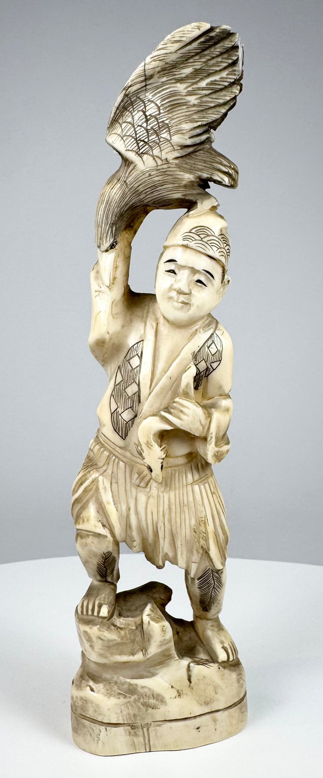 Meiji-era Japanese carved falconer holding an eagle or hawk overhead