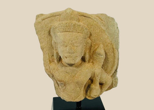 Carved stone fragment of Padmapani (Avalokitesvara) from 12th-century Khmer Empire, Cambodia, showing serene facial features and flowing contours, mounted for display.
