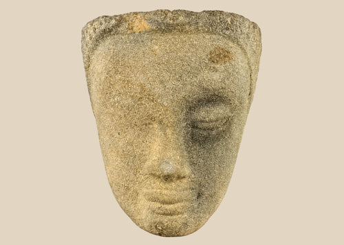 Khmer sandstone head fragment from the Angkor Period, 12th century Cambodia, depicting a serene deity or Buddha with downcast eyes and soft expression, mounted on a wooden display base, photographed on a white background.