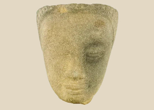 Khmer sandstone head fragment from the Angkor Period, 12th century Cambodia, depicting a serene deity or Buddha with downcast eyes and soft expression, mounted on a wooden display base, photographed on a white background.