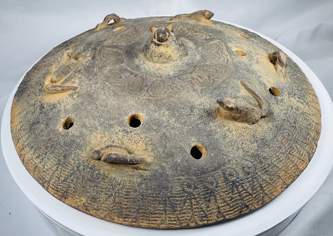 Front view of an ancient Chinese tripod ritual vessel with a removable pierced lid and raised handles.