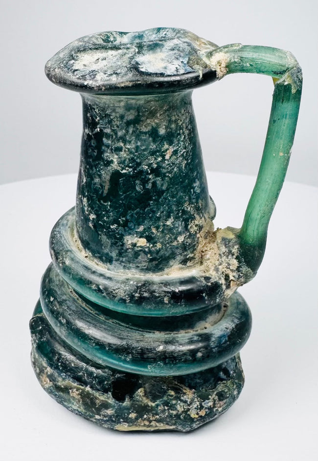 Late Roman glass jug highlighting iridescent weathering, mineral accretions, and hand-blown construction