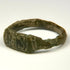 Close-up of ancient bronze ring bezel showing worn geometric engraving and dark green-brown patina