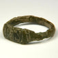 Close-up of ancient bronze ring bezel showing worn geometric engraving and dark green-brown patina