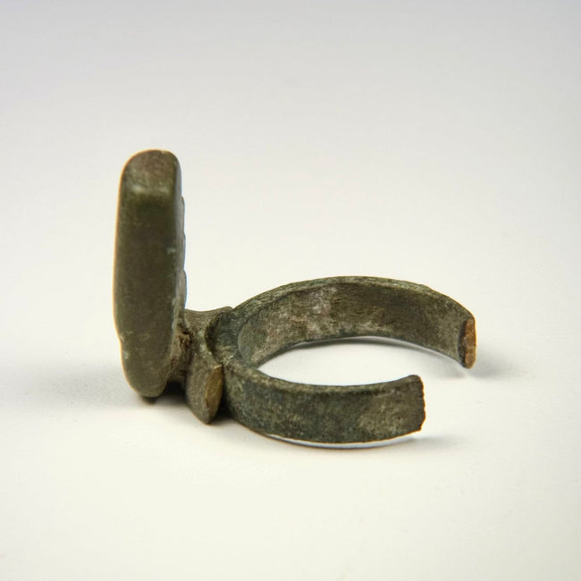 Roman bronze finger key displaying a repaired key attachment, rounded locking teeth, and archaeological surface deposits