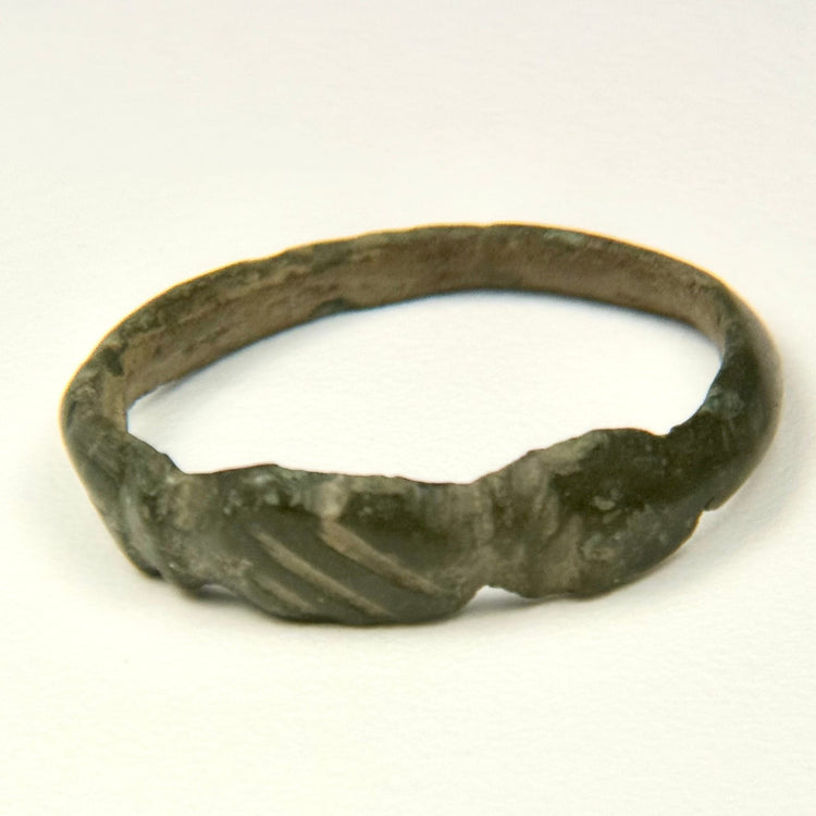 Side view of Late Roman bronze ring showing geometric shoulder grooves and worn archaeological surface