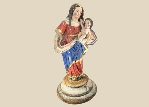Spanish Colonial Madonna and Child statue, circa 1780–1820, hand-carved wood with original polychrome and gilding. Virgin in red and blue robes with gilt highlights holds infant Christ with golden orb. Mounted on original socle with craquelure and age wear.