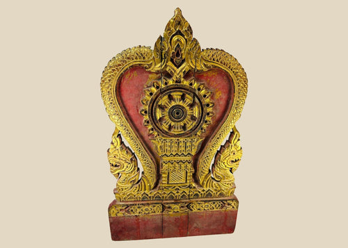 Thai Buddhist shrine panel carved from teakwood, gilded over red lacquer, featuring central dharmachakra and twin naga serpents, late 19th century, Rattanakosin/Lanna tradition, 24.5 x 15 inches
