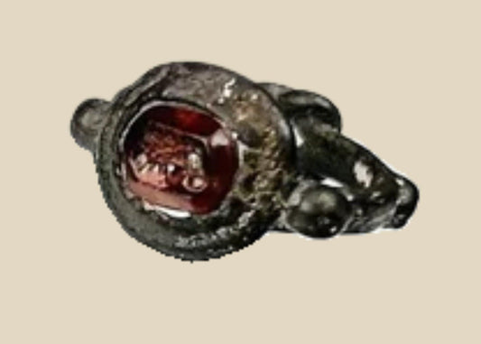 Ancient silver ring from the Eastern Mediterranean or Near East, Late Roman to Early Byzantine period (circa 300–600 CE), featuring a deep red garnet intaglio engraved with symbolic imagery, flanked by decorative silver nodes, preserving its historical elegance and craftsmanship.