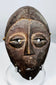 Central African Lega mask featuring simplified symbolic facial features and original fiber cord remnants.
