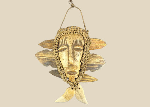 Mid-20th-century Lega tribal pendant mask from the Congo, carved bone face with braided fiber collar, wood backing, and hanging cord, displayed on a black stand against a white background.