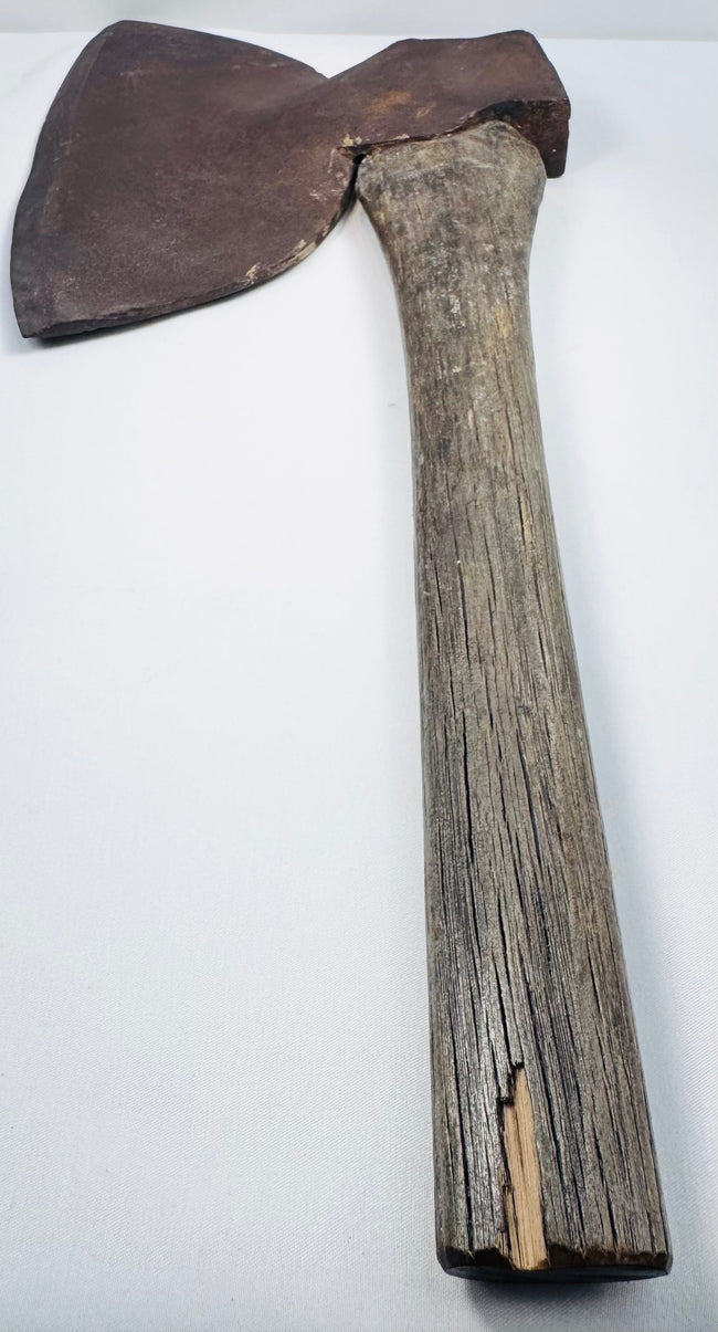 Historic American logging axe photographed from a low side angle, showing the steel head secured to its original wooden handle.