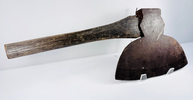 Angled close-up of the M.H. Jones &amp; Co. axe head highlighting the curved cutting edge and heavily patinated steel surface.