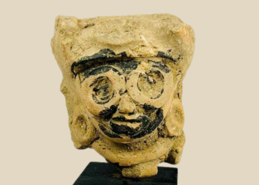 Late Classic Period Mesoamerican ceramic head fragment, circa 500–900 CE, with finely modeled features, large circular earrings, and traces of black pigment, mounted on a display stand.
