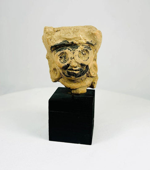 Late Classic Period Mesoamerican ceramic head fragment, circa 500–900 CE, with finely modeled features, large circular earrings, and traces of black pigment, mounted on a display stand.