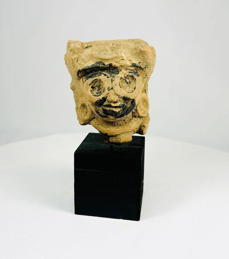 Late Classic Period Mesoamerican ceramic head fragment, circa 500–900 CE, with finely modeled features, large circular earrings, and traces of black pigment, mounted on a display stand.