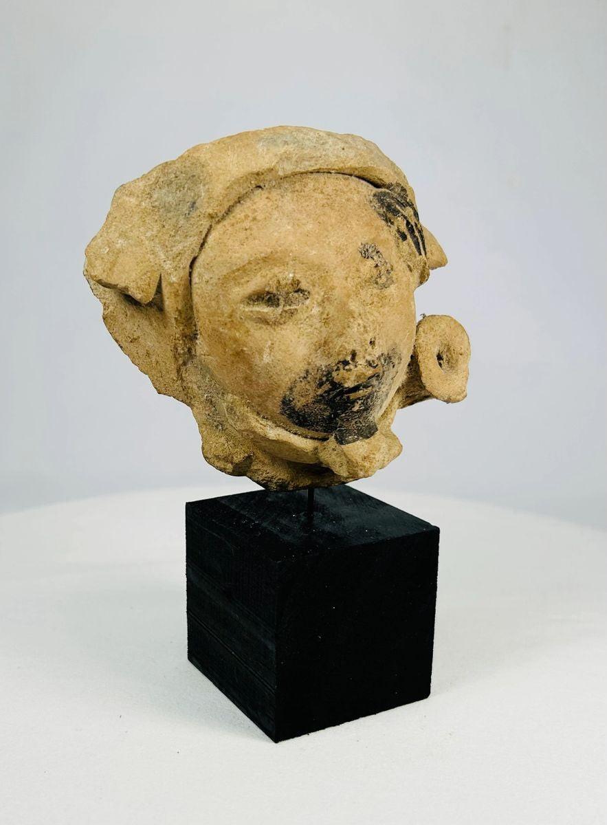 Late Classic Period Mesoamerican ceramic head fragment, circa 500–900 CE, with expressive facial features, traces of black pigment, and a detailed turban-like headpiece.
