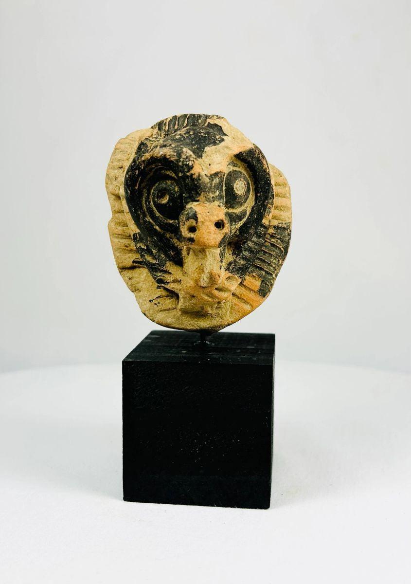 Pre-Columbian terracotta mask fragment from Mesoamerica, Classic Period (500–900 AD), depicting an animal face with bold eyes and snout, incised patterns, and traces of black pigment.