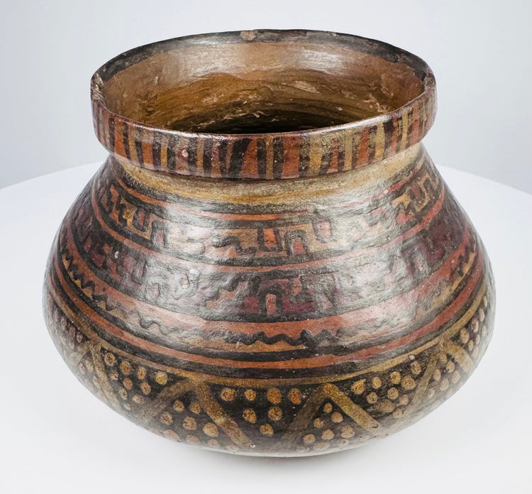 Side view of ancient Mesoamerican redware bowl showing horizontal geometric bands and dotted triangular motifs