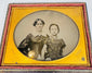 Victorian ambrotype of a woman and child seated together within an ornate gilt-brass oval presentation mat