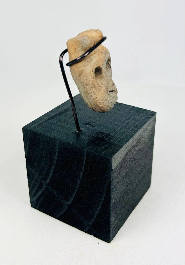 Ancient carved bone face pendant from Western Mexico showing stylized features and patina