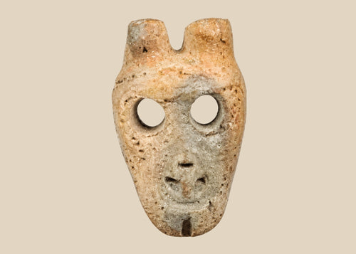 Miniature anthropomorphic mask pendant carved from bone, featuring hollowed eyes, prominent nose ridge, open mouth, and twin suspension holes; mounted on custom display stand; Western Mexico, Colima/Nayarit region, circa 300 BCE–300 CE.