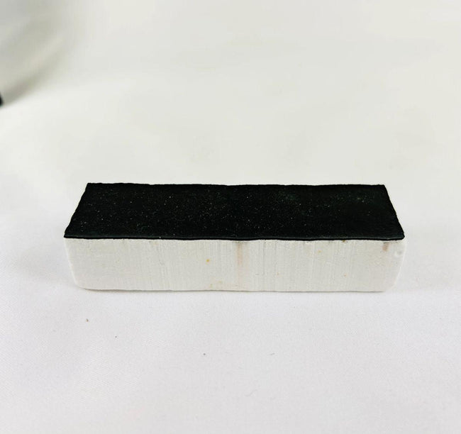 Authentic NASA Space Shuttle Thermal Protection System (TPS) tile from the 1980s, made of silica-based ceramic with black Reaction Cured Glass coating, used for reentry heat resistance, preserved in NASA-issued display case.