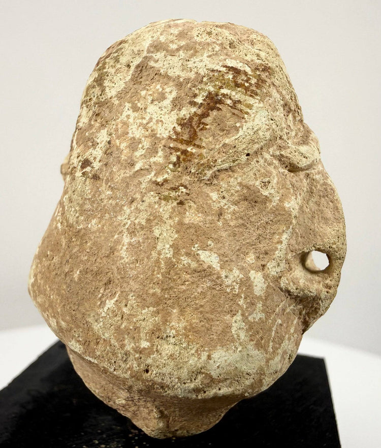Ancient-style Near Eastern sculptural fragment featuring deeply recessed eyes and distinctive geometric facial carving.