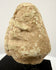 Side profile of weathered stone idol head showing textured porous surface and brow ridge