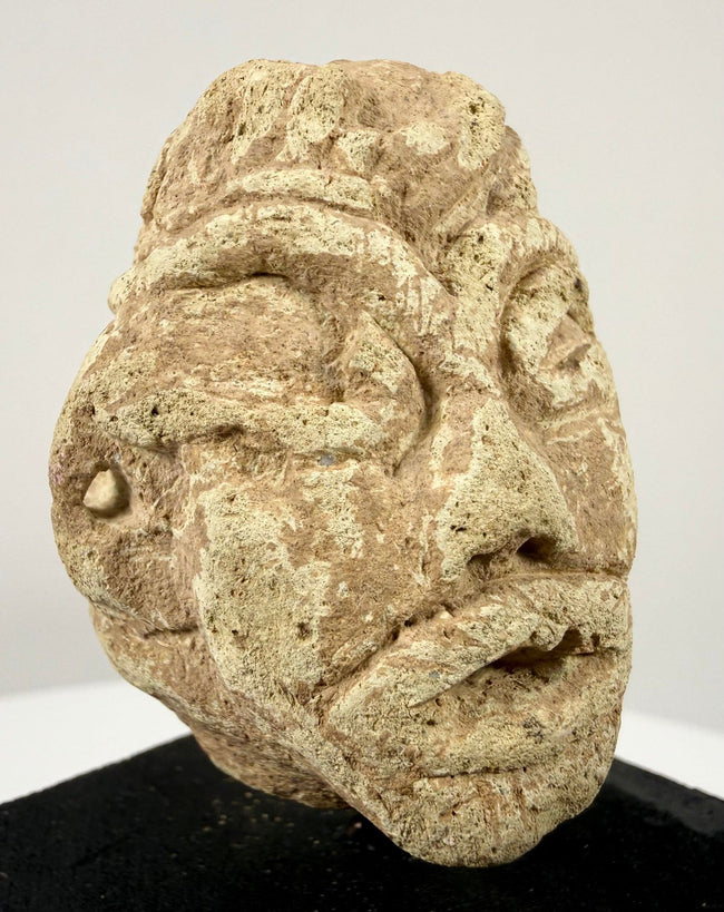 Angled view of ancient stone head artifact highlighting almond-shaped eyes and defined ear