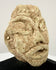 Angled view of ancient stone head artifact highlighting almond-shaped eyes and defined ear
