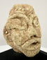 Angled view of ancient stone head artifact highlighting almond-shaped eyes and defined ear