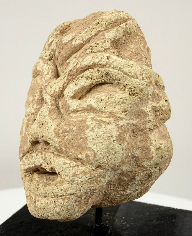 Historic Mesopotamian-style idol head displaying a broad flat nose, wide mouth, and natural surface erosion.