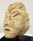 Historic Mesopotamian-style idol head displaying a broad flat nose, wide mouth, and natural surface erosion.