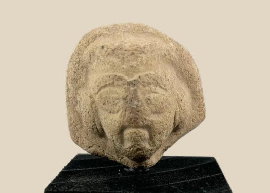 Fragmentary terracotta head with stylized arched brows, almond-shaped eyes, defined beard and mustache, and detailed coiffure; likely part of a votive or ritual figure from the Near East/Eastern Mediterranean, circa 1st millennium BCE; mounted on a custom black display base.