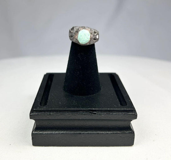 Ancient Neo-Assyrian silver ring from Mesopotamia (modern-day Iraq), 9th–7th century BCE, featuring a raised turquoise bezel and engraved winged serpent with mythical beast motifs. Silver band with natural patina showcases Assyrian craftsmanship, symbolizing divine protection, authority, and spiritual power.
